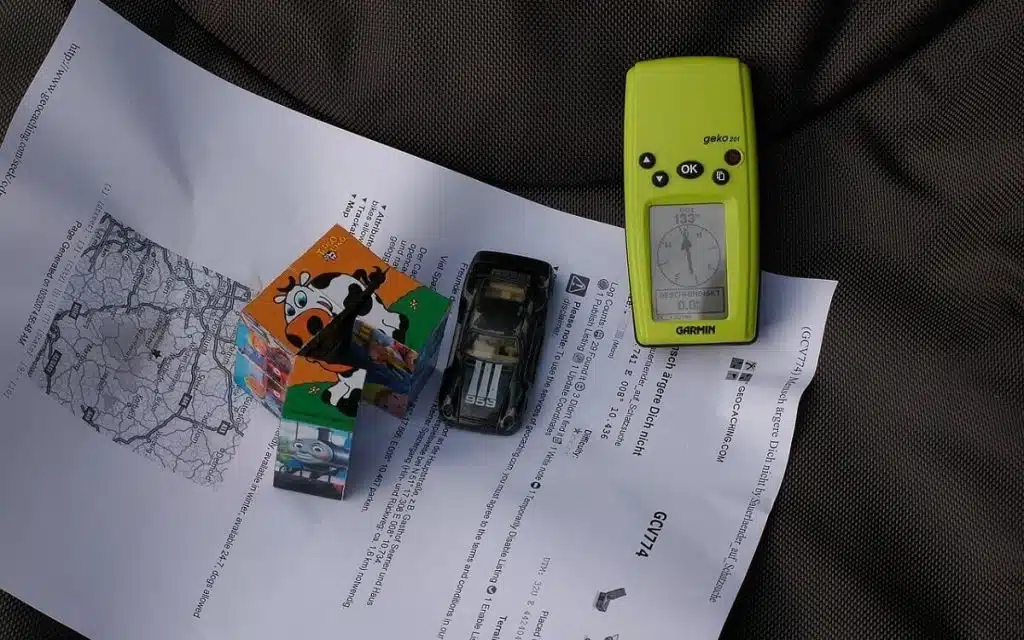 Kompass und Spielzeuge auf einem Blatt Papier mit Geocaching Anweisungen