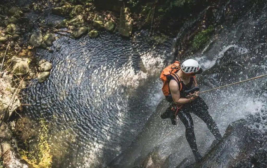 EIn Mann, der an einem Seil in einem Wasserfall hängt